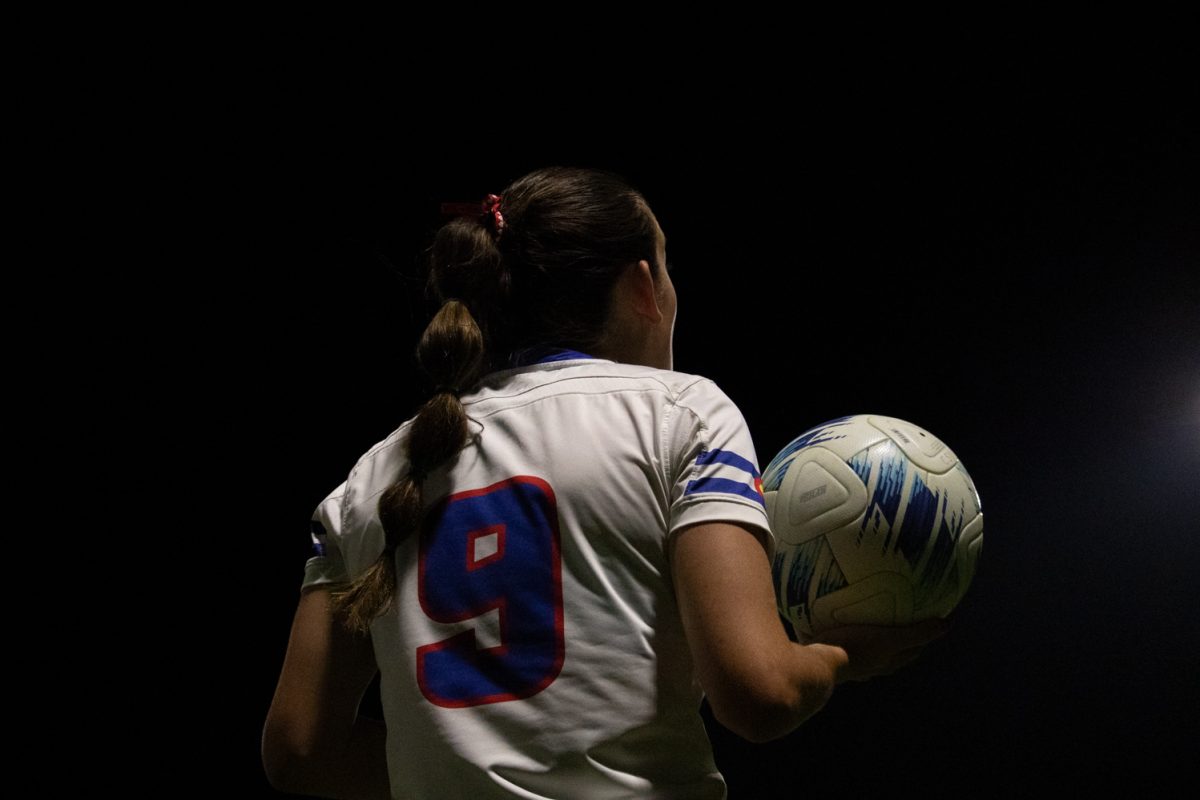 A soccer player stands holding a ball.