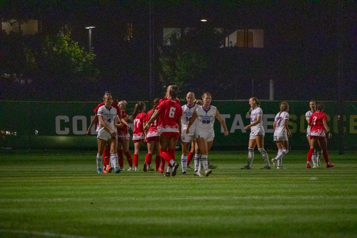 Two lines of soccer players pass each other giving high fives.