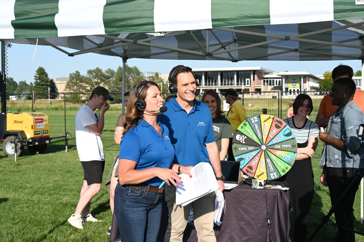 a man and a woman reporter in blue shirts talk in front of a student run booth