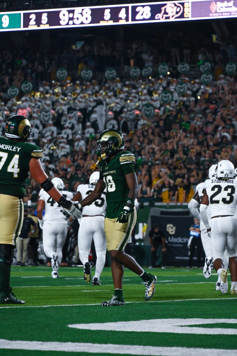 Two Colorado State players shake hands with each other as multiple University of Colorado players walk away after a play finishes.