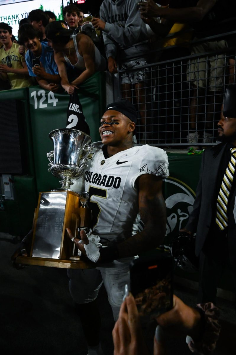 A player in white and black holds up a silver cup like trophy