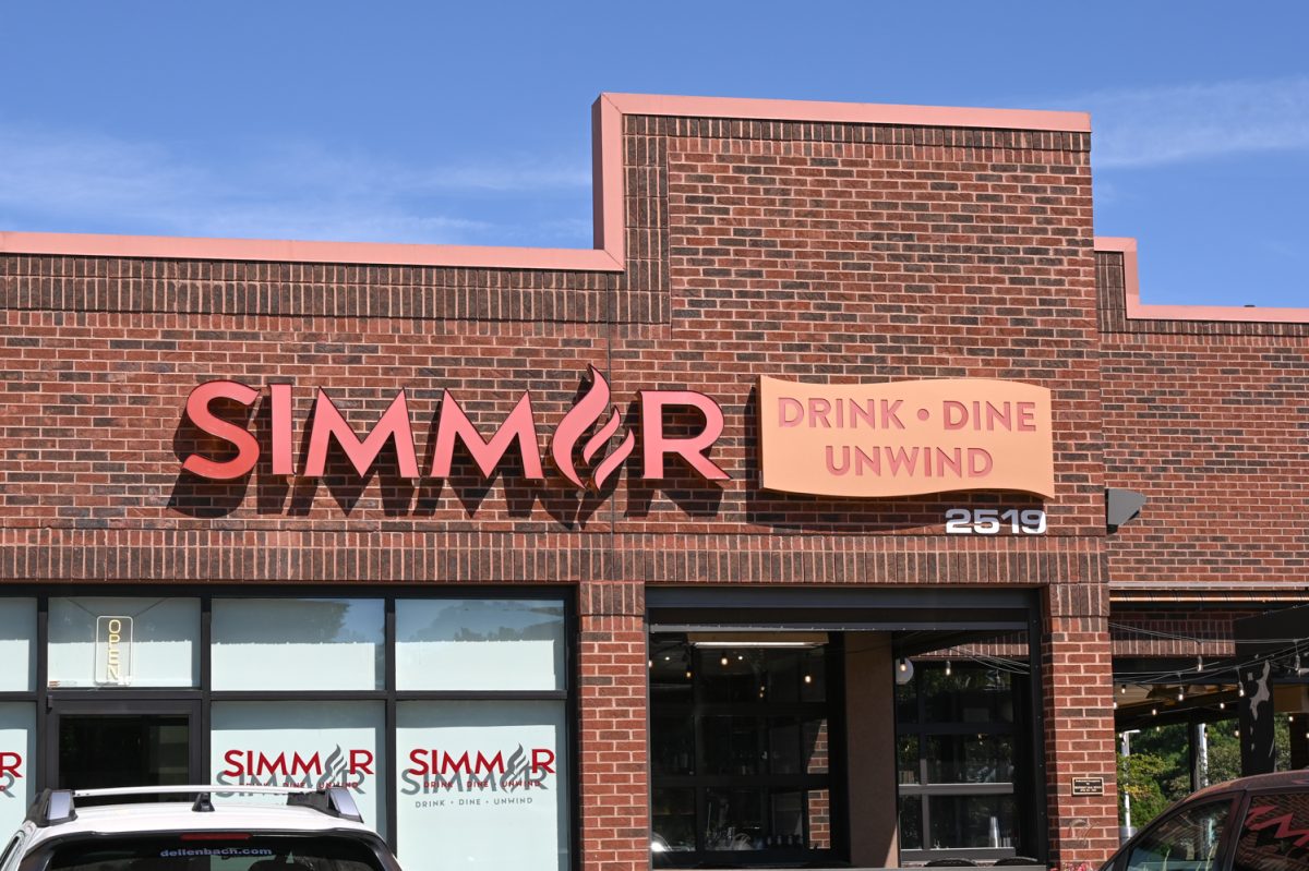 The outside of a red brick building titled "Simmer," and cars out front