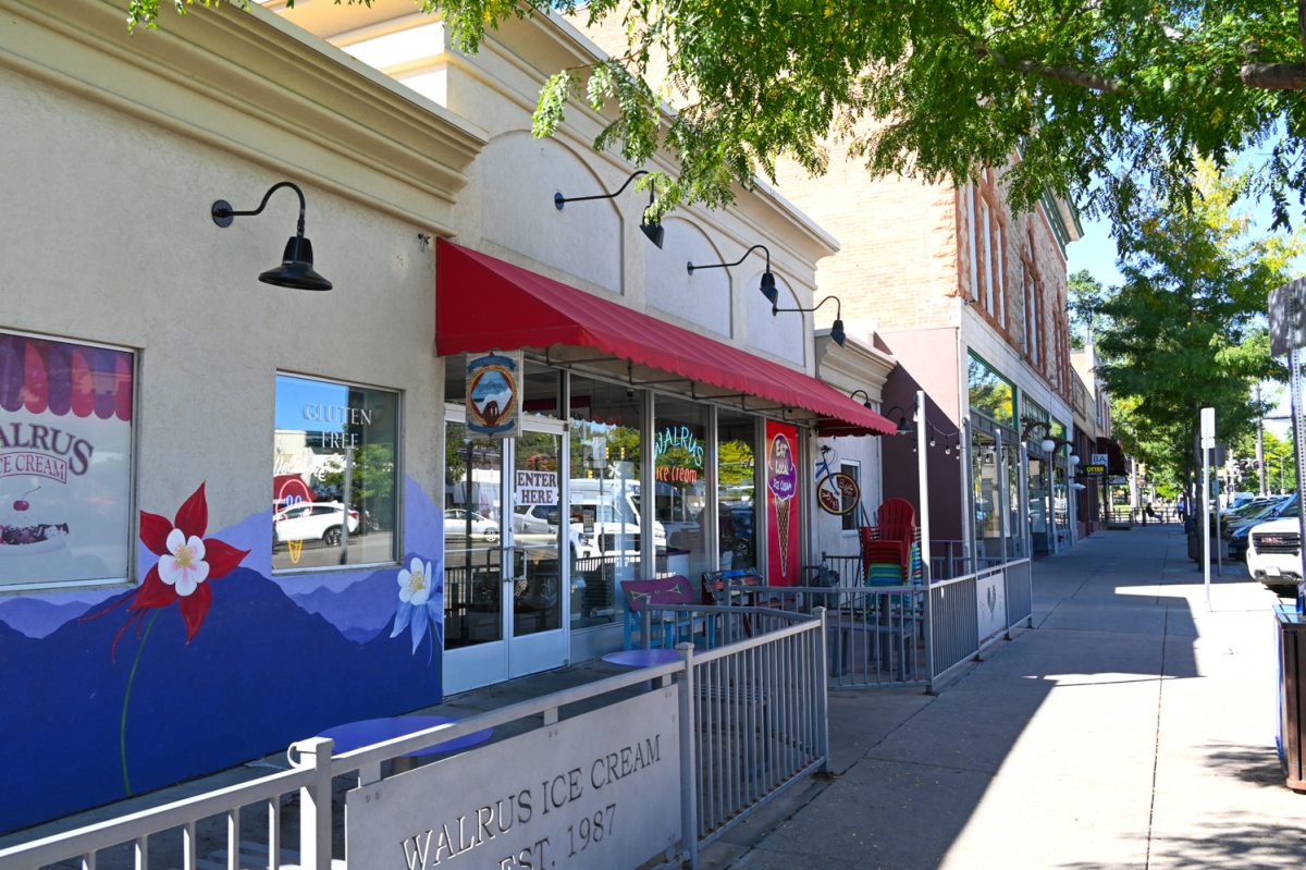 A yellow and purple storefront with a red awning and a grey fence out front