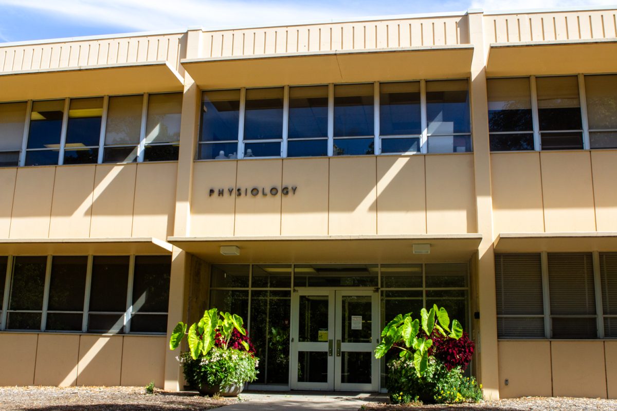 On a sunny day, a tan building with the word "Physiology" is devoid of people.
