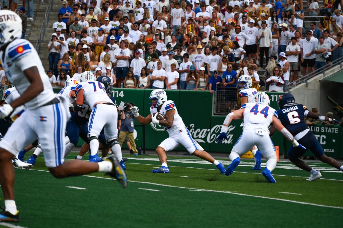 a player in blue and white runs with a brown ball