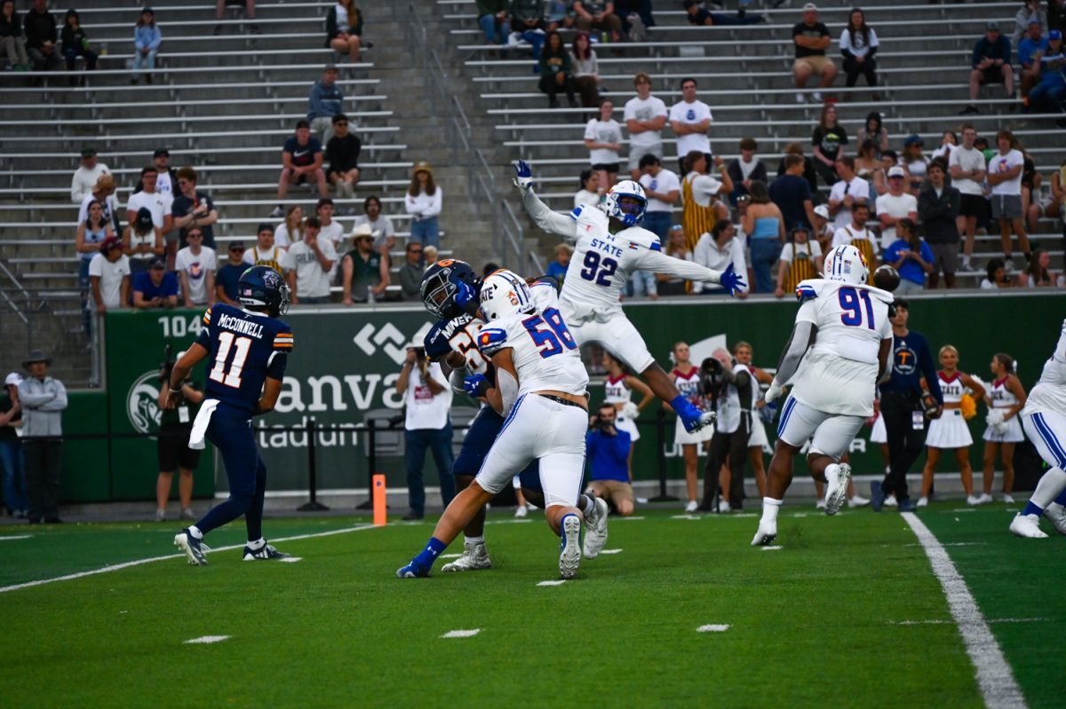 A player in royal blue and white goes to tackle a player in navy blue and orange.