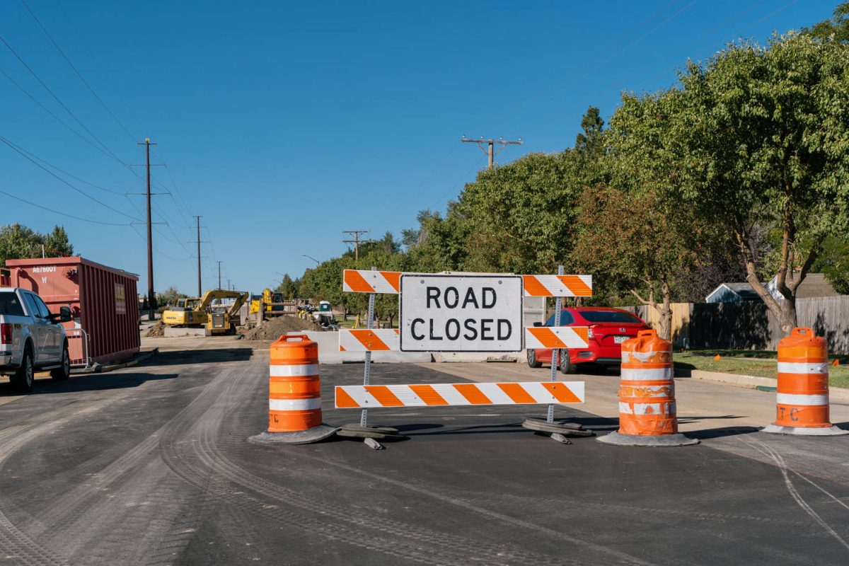 A road closed sign surrounded by yellow cylindrical cones.