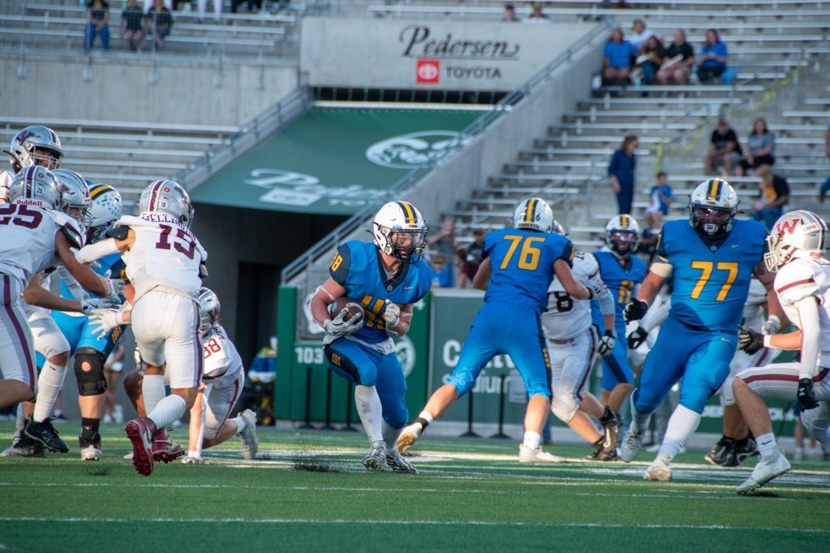 football player in blue running through hole full of blue and white uniform football players