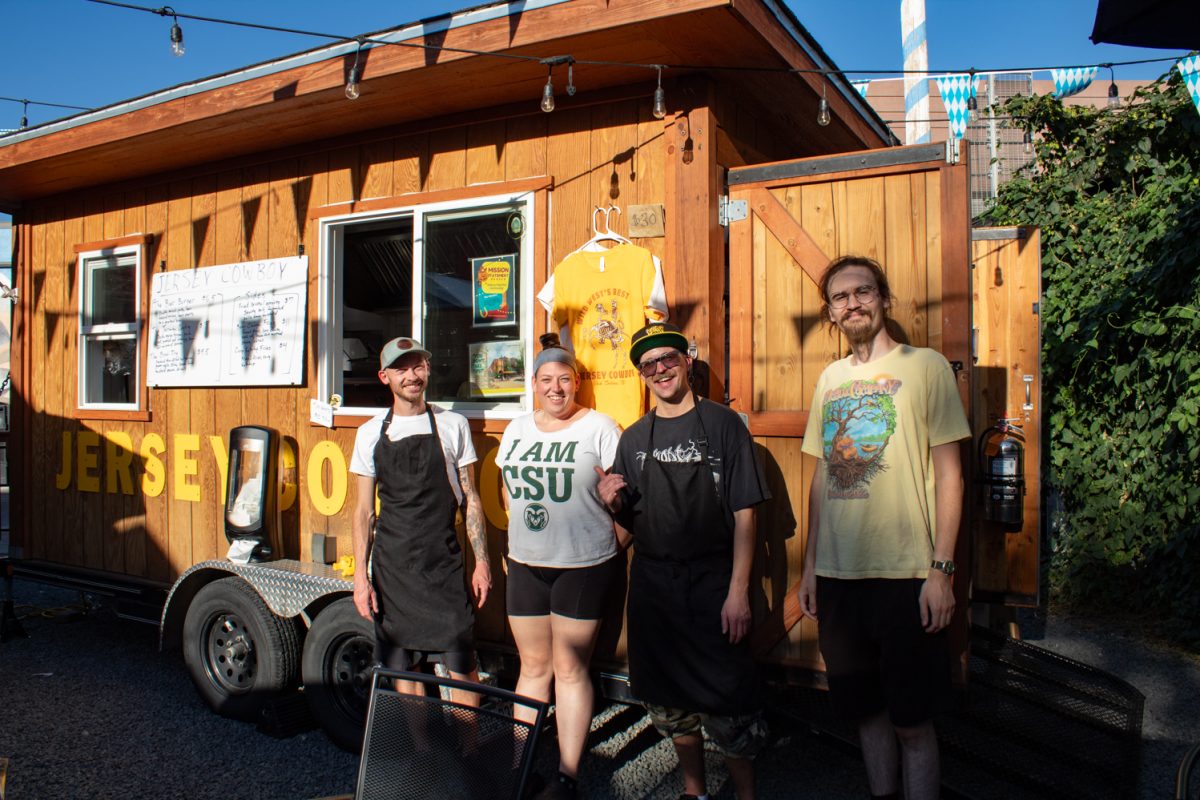 Four people stand in front of a light wood-stained food truck called Jersey Cowboy.