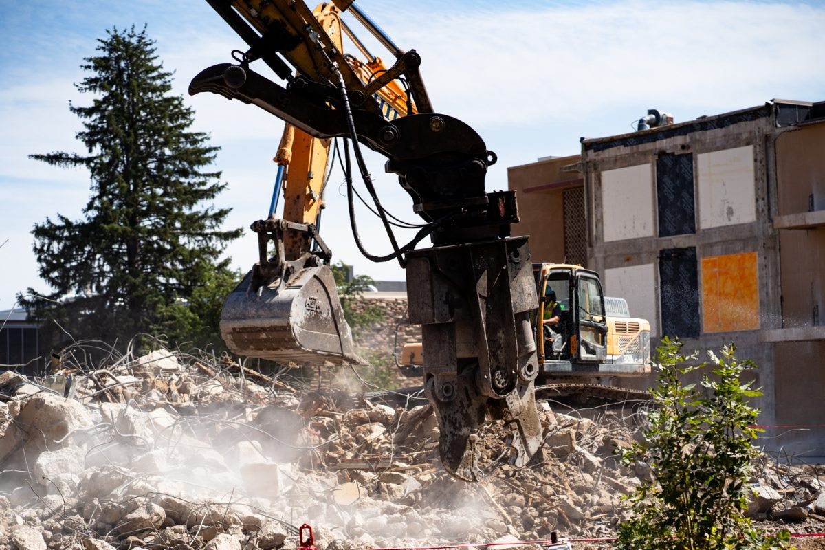 A backhoe sits on a pile of rebar and broken concrete.