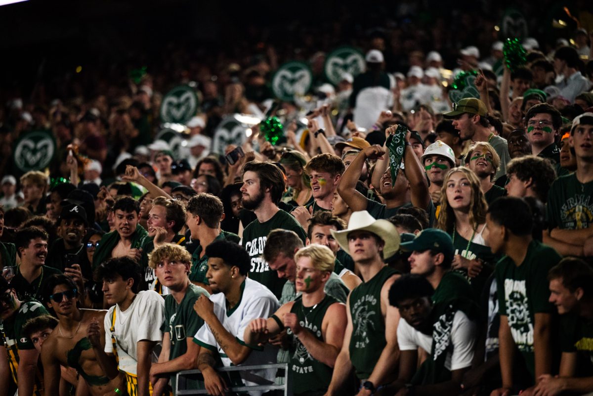 A crowd of students in green. Some of them look pensive or nervous.