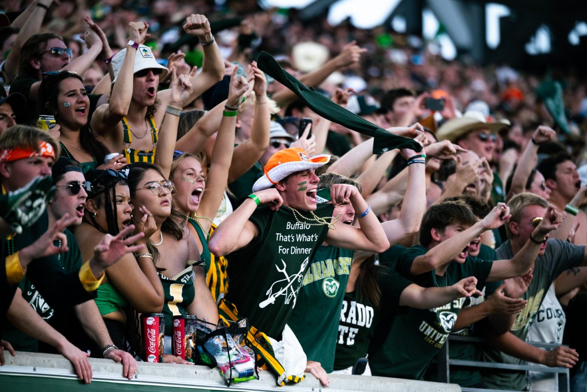 A crowd of people wearing green and yellow cheer.