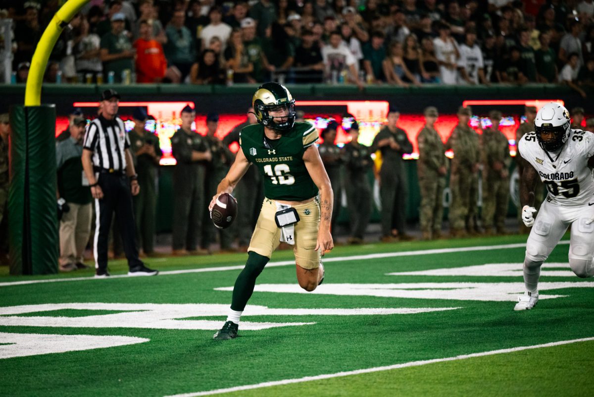 A football player in green and gold runs with the football.