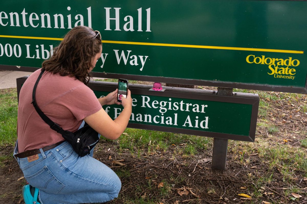 M.M, the Director of Octopi Operations for Octopi of CSU takes a photo of a recently hidden octopi on the sign for Centennial Hall to post on the group's Instagram page as a clue for finders. M.M and the rest of the group are anonymous to preserve the integrity and mystery of the group.