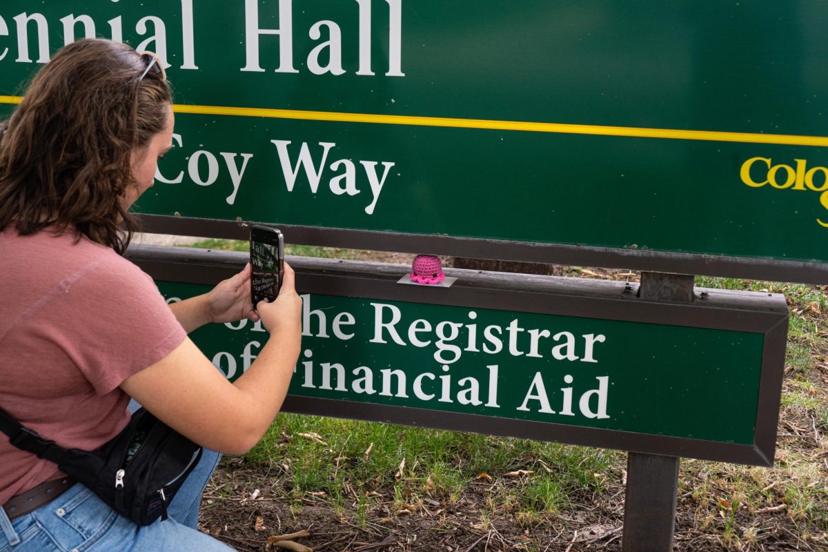 M.M, the Director of Octopi Operations for Octopi of CSU takes a photo of a recently hidden octopi on the sign for Centennial Hall to post on the group's Instagram page as a clue for finders. M.M and the rest of the group are anonymous to preserve the integrity and mystery of the group.