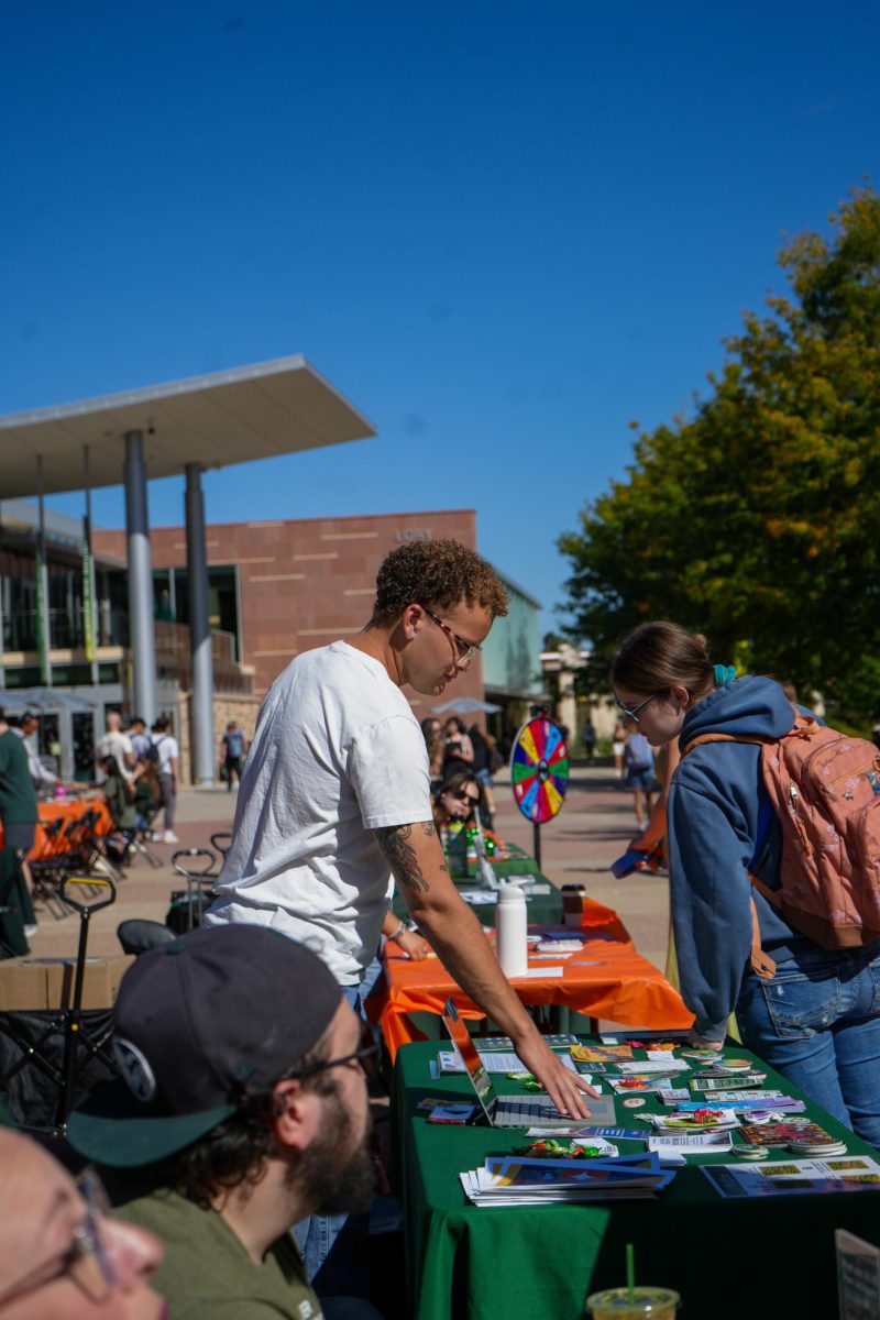 Alex Diggs, a representative of the Cultural Resource Centers and the Office of Inclusive Excellence adjusts tabling materials on Sept. 20 at the Wellness Wonderland event. The event, hosted by the Associated Students of Colorado State University, strove to provide wellbeing resources to students. 