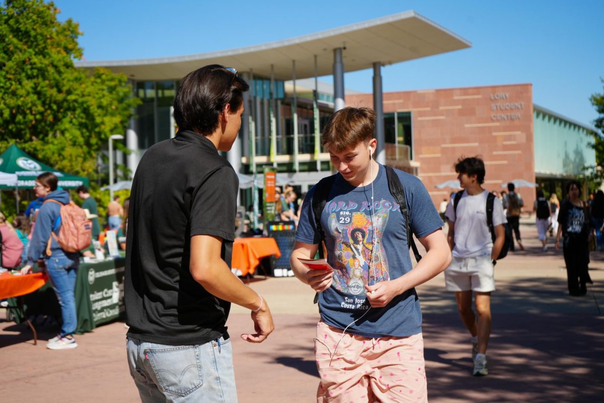 Associated Students of Colorado State University Director of Public Relations Jospeh Godshall hands a flier to a student advertising Wellness Wonderland on Sept. 20. The event, held on The Plaza, aimed to provide wellness resources to students. 