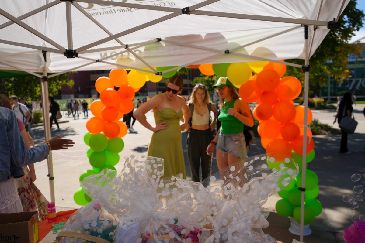 Associated Students of Colorado State University Director of Basic Needs Jorja Whyte and Deputy Director of Basic Needs Lauren Johnson examine the event set up with a student on Sept. 20. The event hosted a raffle for prizes and free resources for students. 