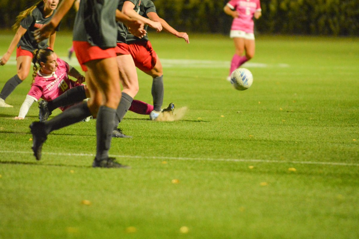 A soccer player sliding on the ground with a ball