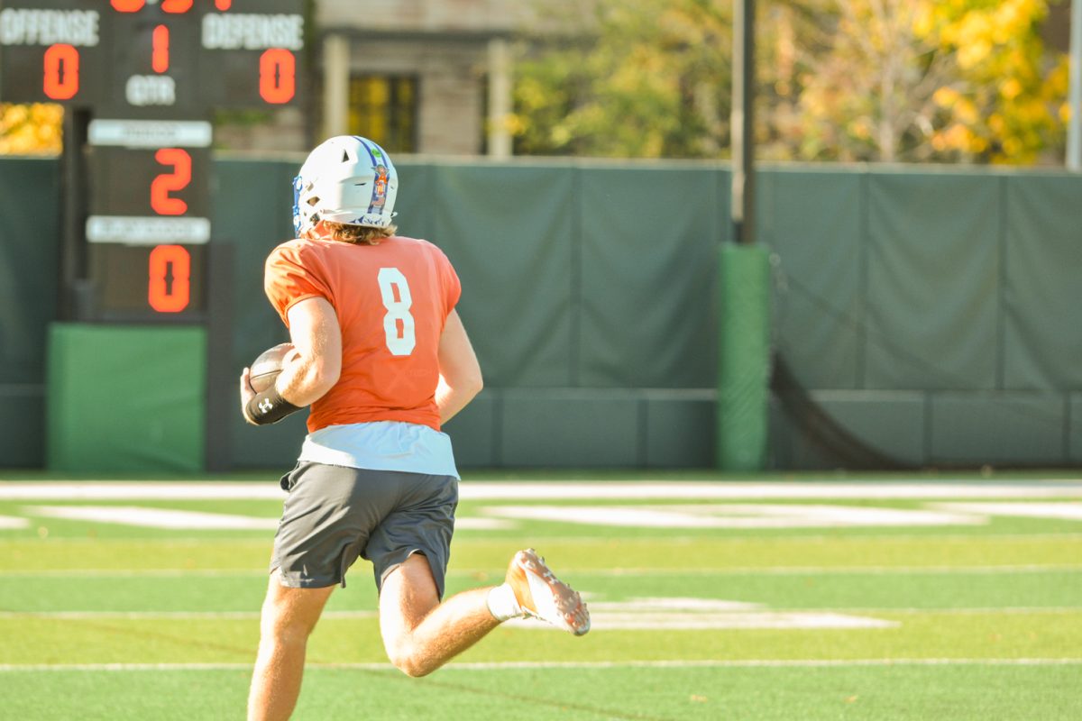 A CSU football player running with the ball down the field during practice. 