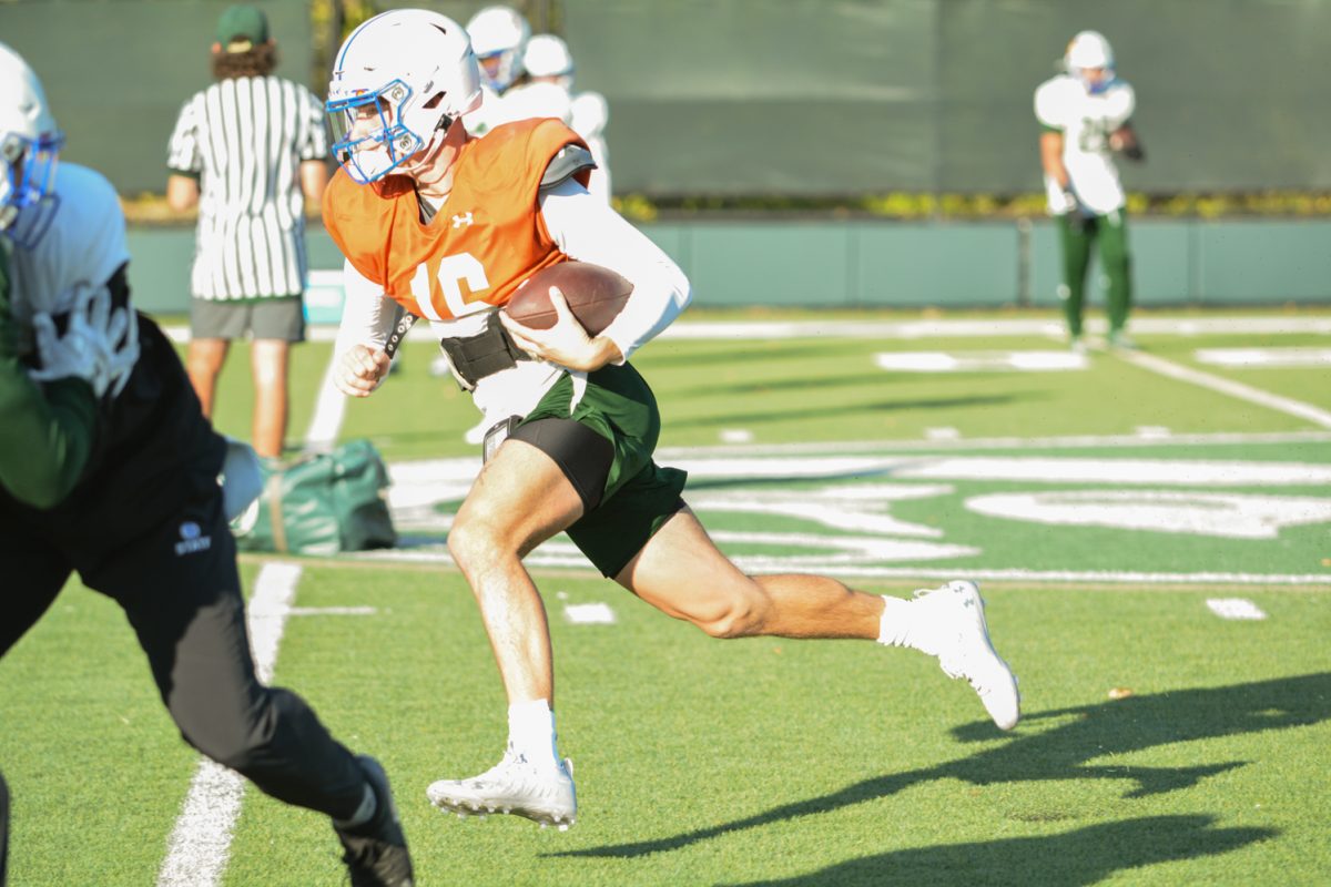 Quarterback runs with the ball during a play during morning practice. 