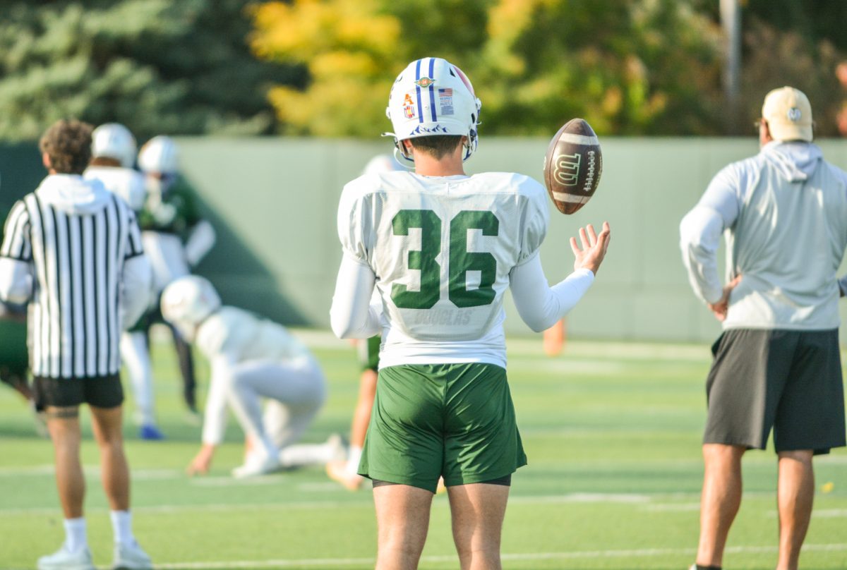A CSU football player throwing the ball while waiting to run a drill. 