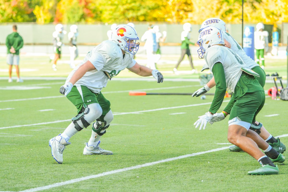 Three CSU football players running a drill during practice. 