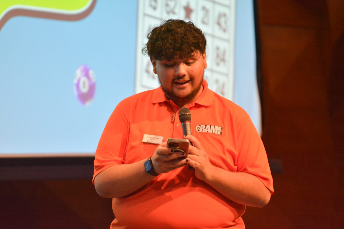 Speaker with an orange shirt on holding a microphone