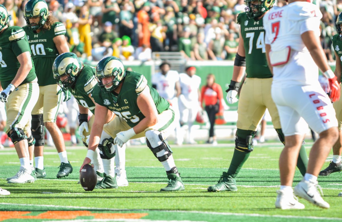 Player in a green and gold jersey holding a football.