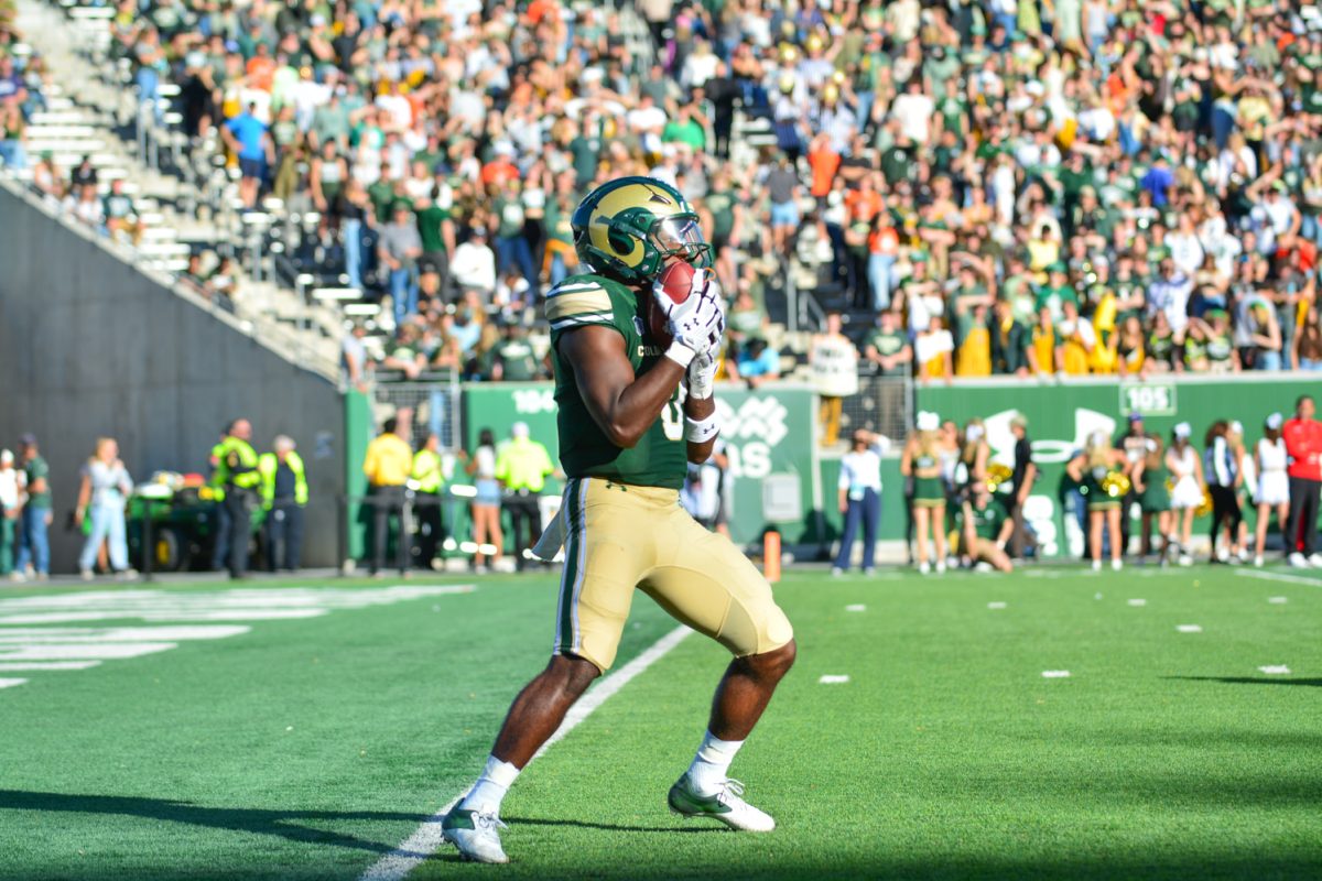 Football player in green jersey holding a ball to his face