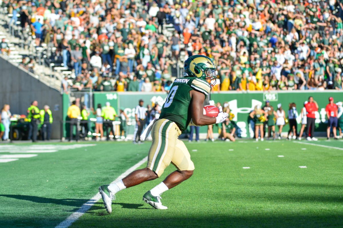 Football player in green jersey holding a ball