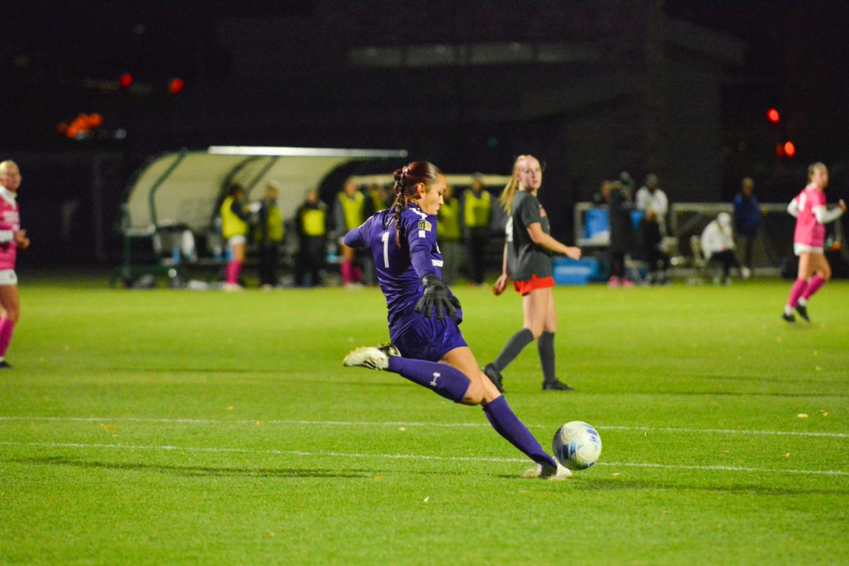 A player with a blue shirt and shorts kicking a ball