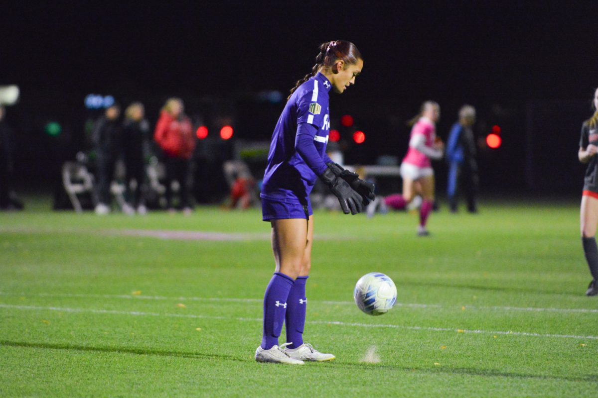Girl in blue jersey throwing ball at ground.