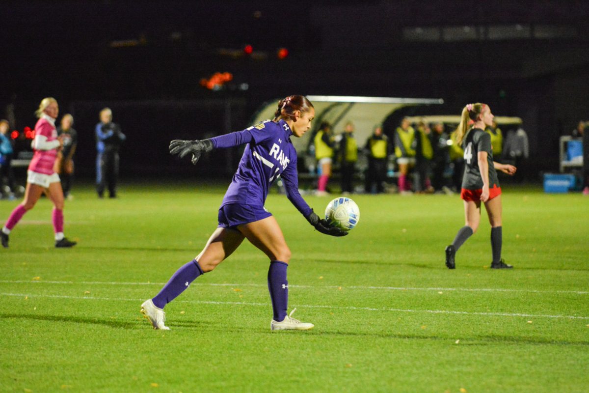 A girl in a blue shirt and blue shorts kicking a ball
