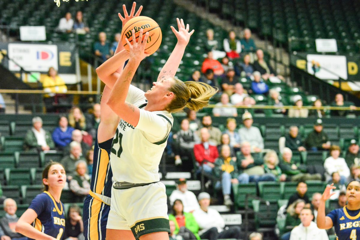 A player in a white jersey jumps with a basketball in her hand