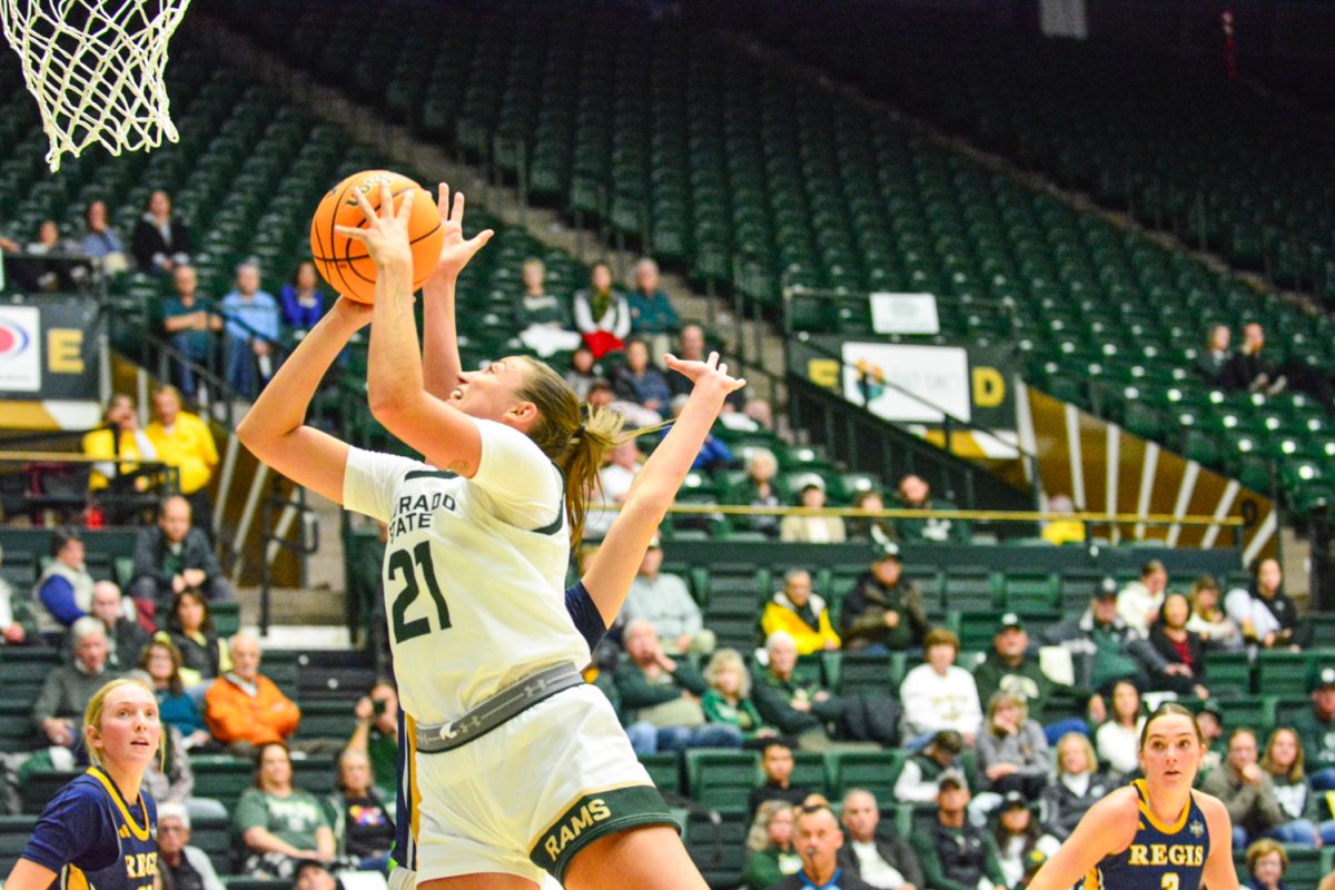 Girl player in a white and green jersey jumping with a ball in her hand