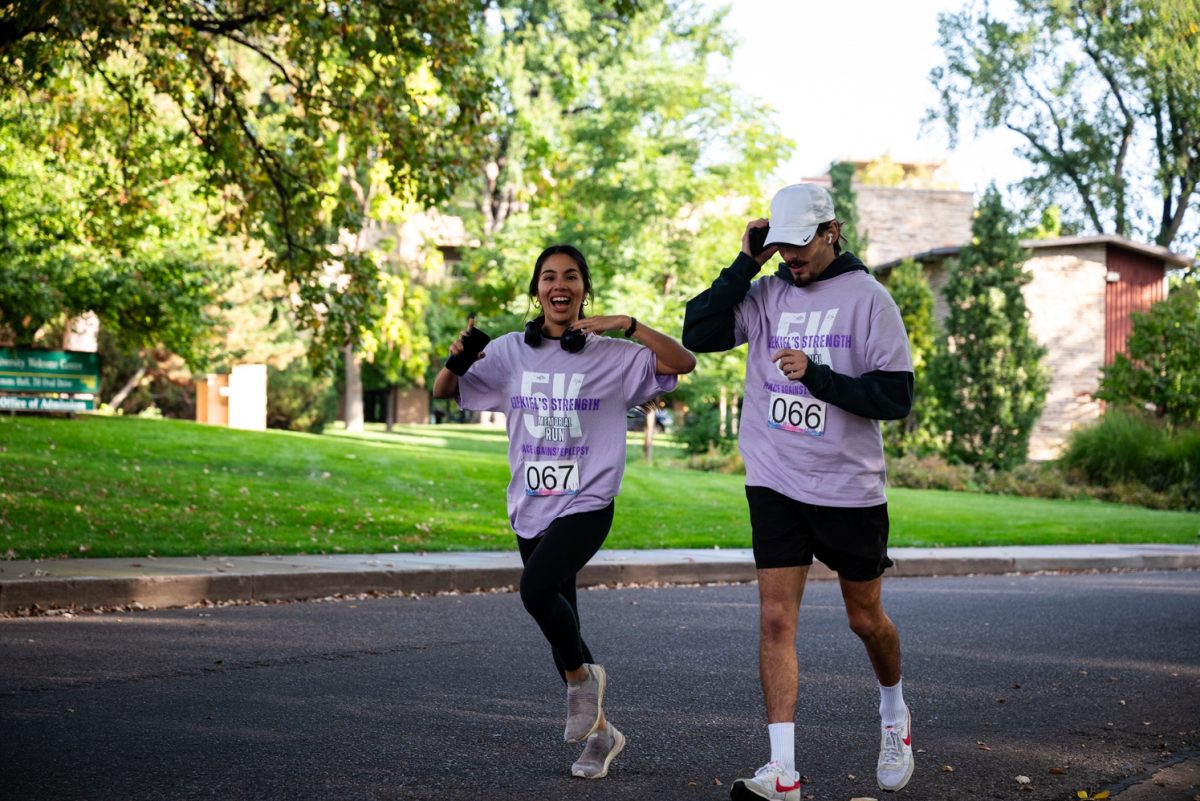 A woman and a man in light purple shirts run together on a road.