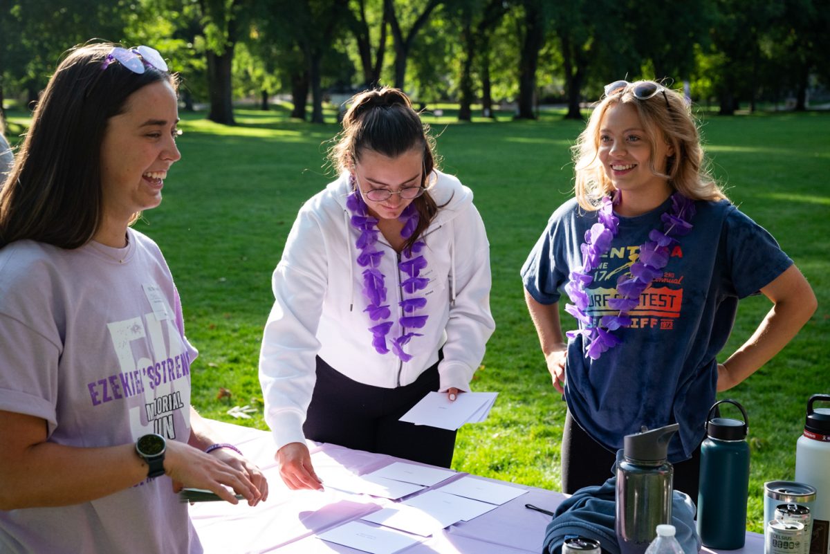 Three women smile together while placing thank you cards on a table.