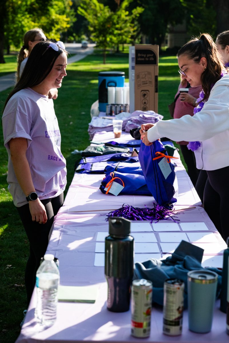 Two women smile and pack blue drawstring bags.