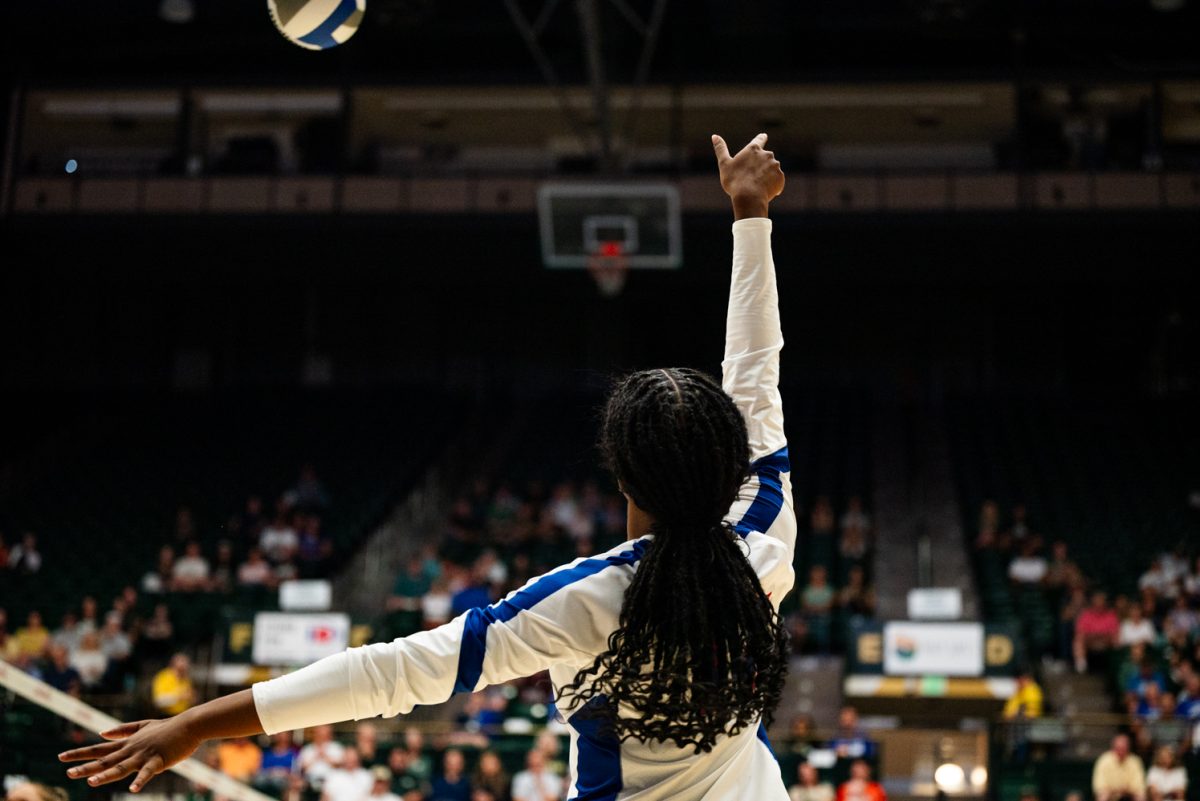 A volleyball player in white and blue hits a volleyball.