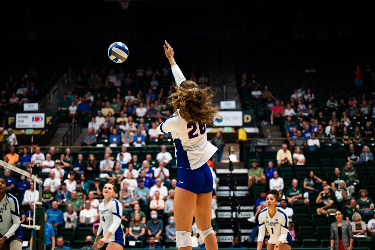 A volleyball player in white and blue hits a volleyball.