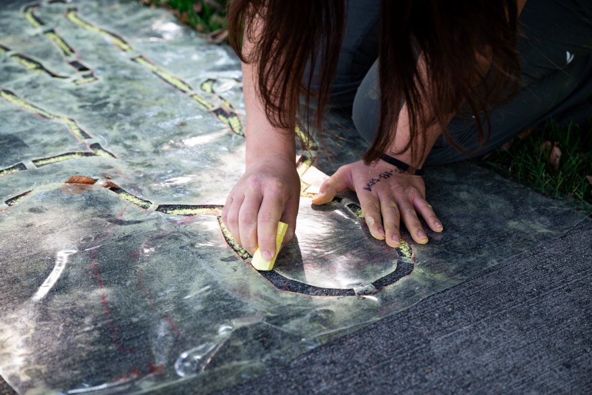 A person tracing an outline in yellow chalk.