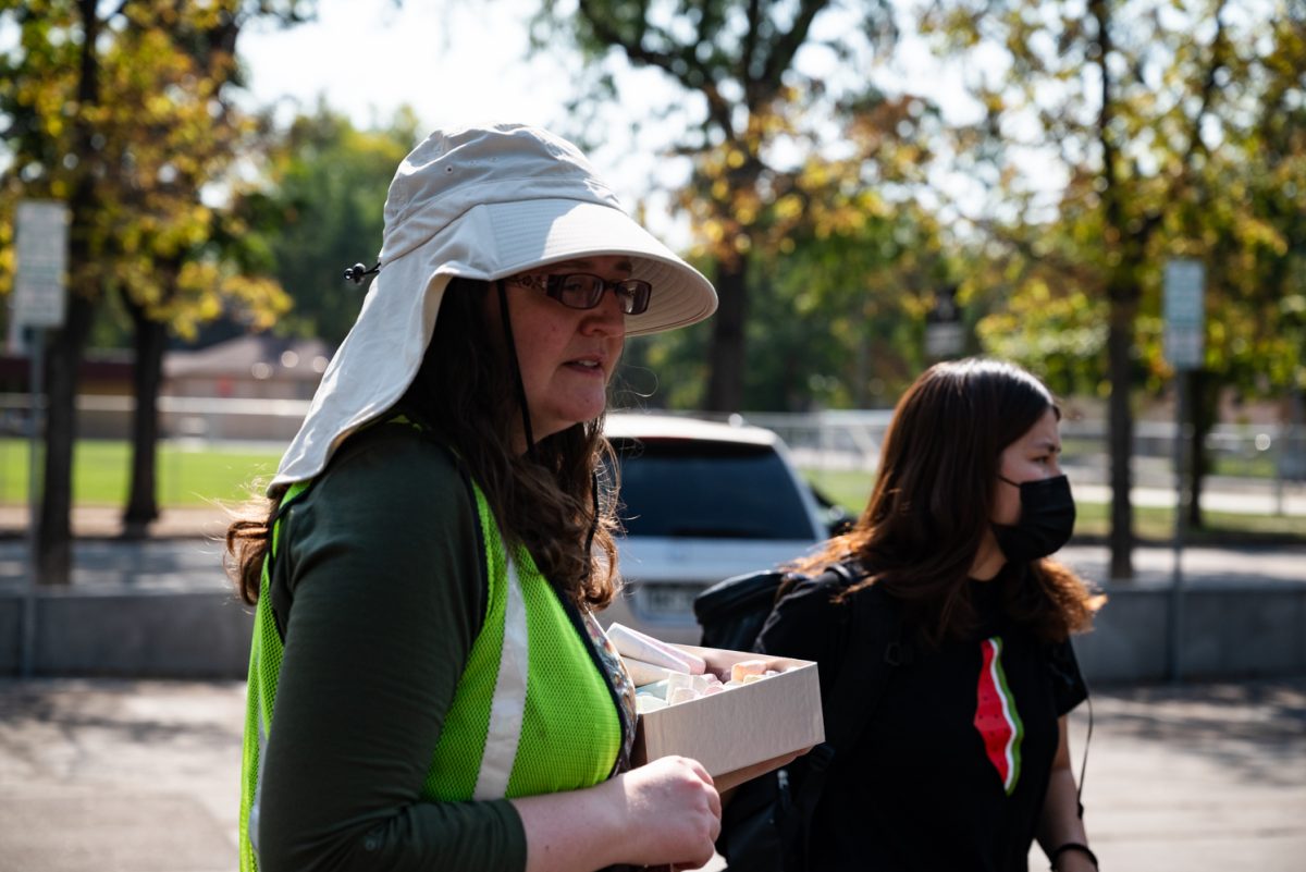 A woman in a neon construction vest holds a box of chalk.