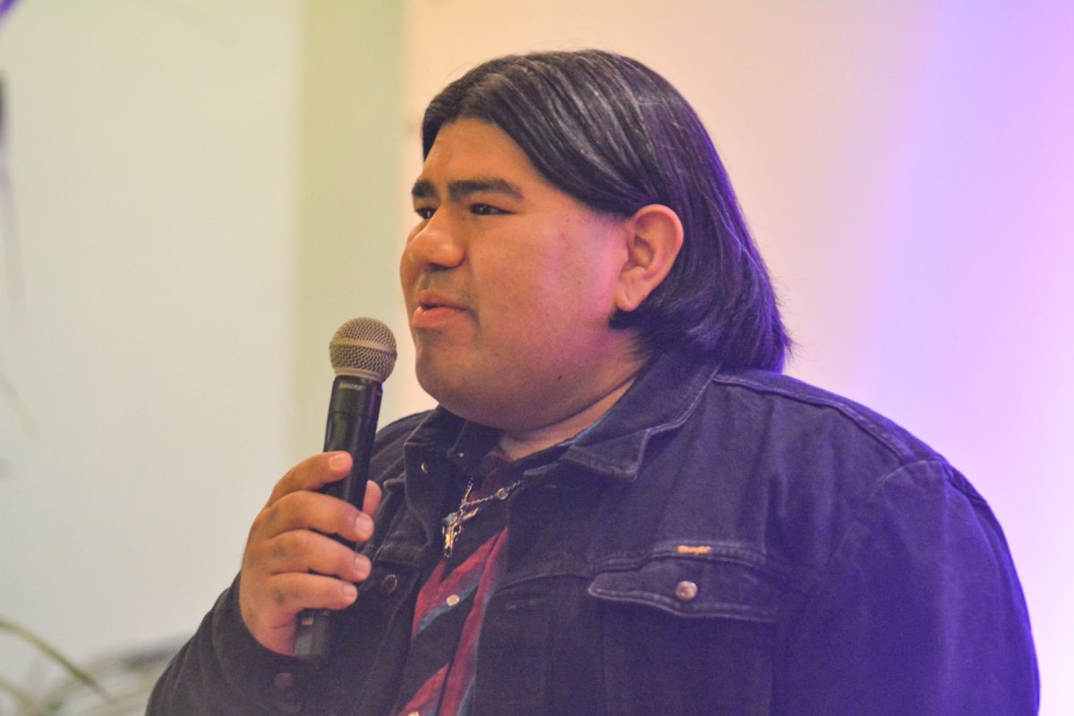 A speaker holding a microphone looking out towards the crowd