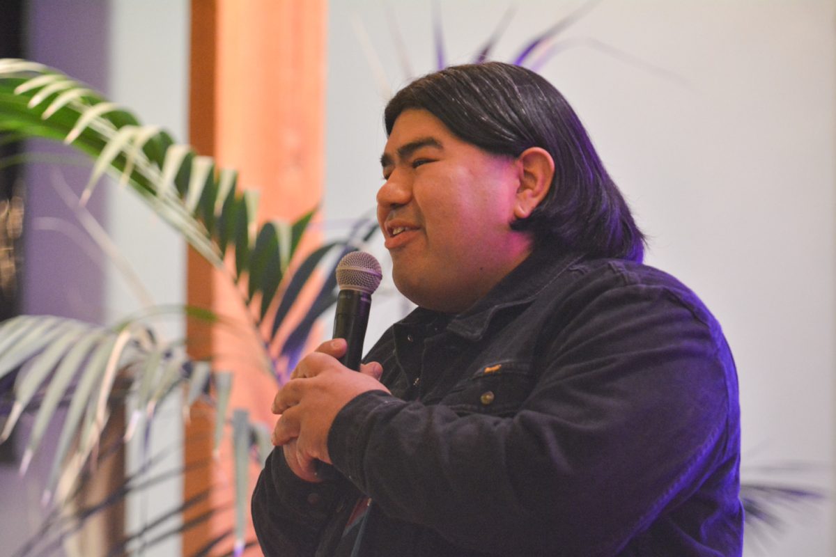 A speaker holding a microphone looking towards the crowd