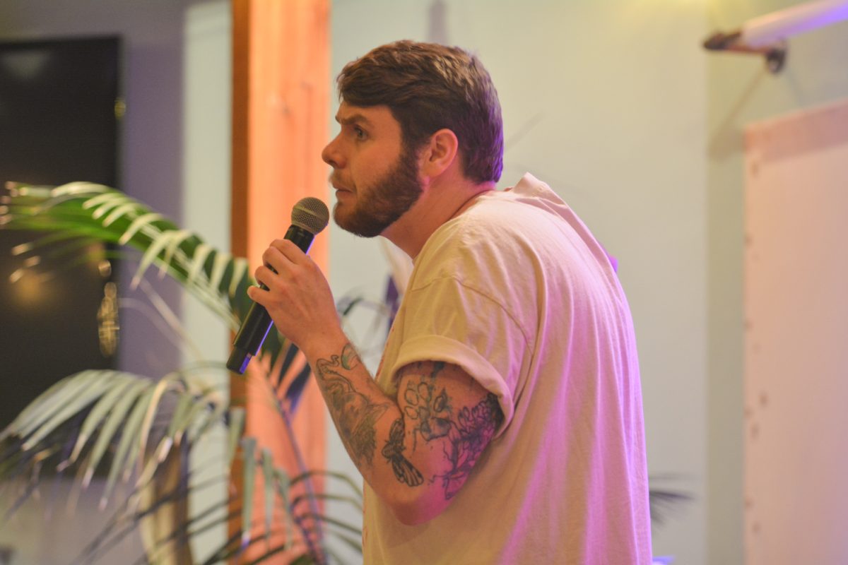 A speaker holding a microphone looking towards the crowd.