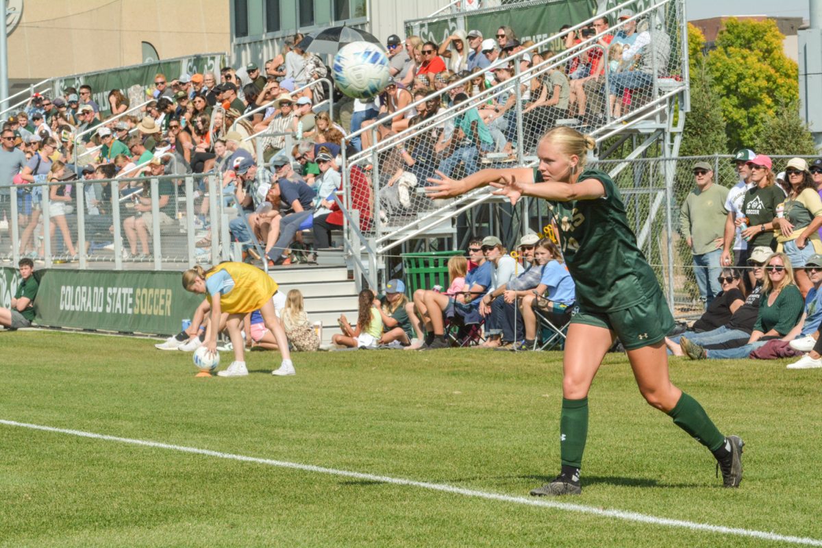 A soccer player throwing a soccer ball with a crowd behind her