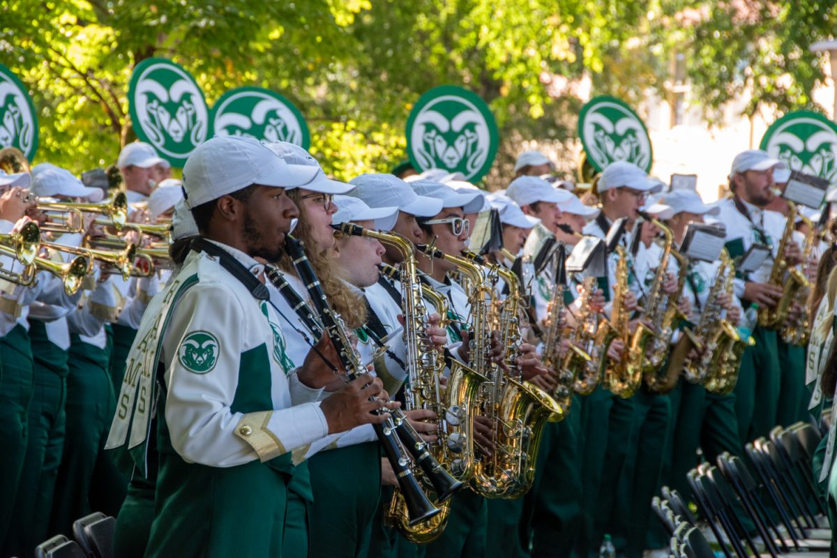 marching band playing shiny instruments with csu logo in background