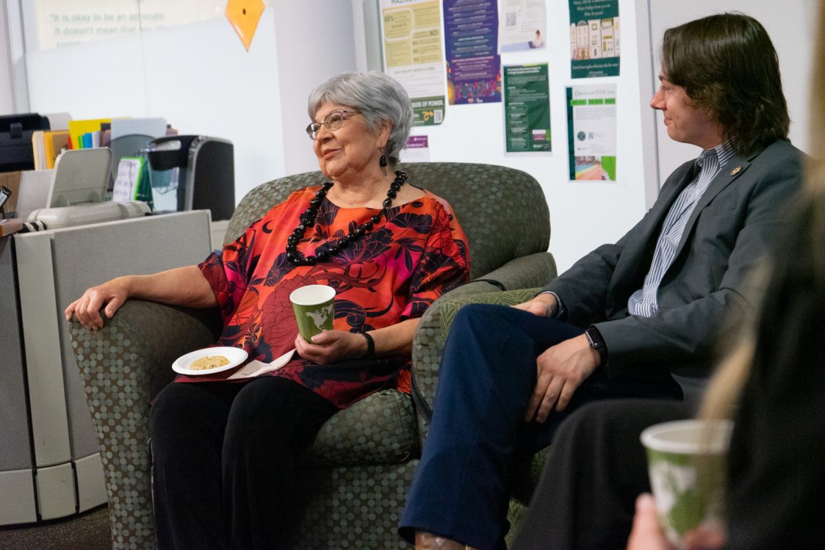 An older woman sits next to a young man who is listening to her speak.