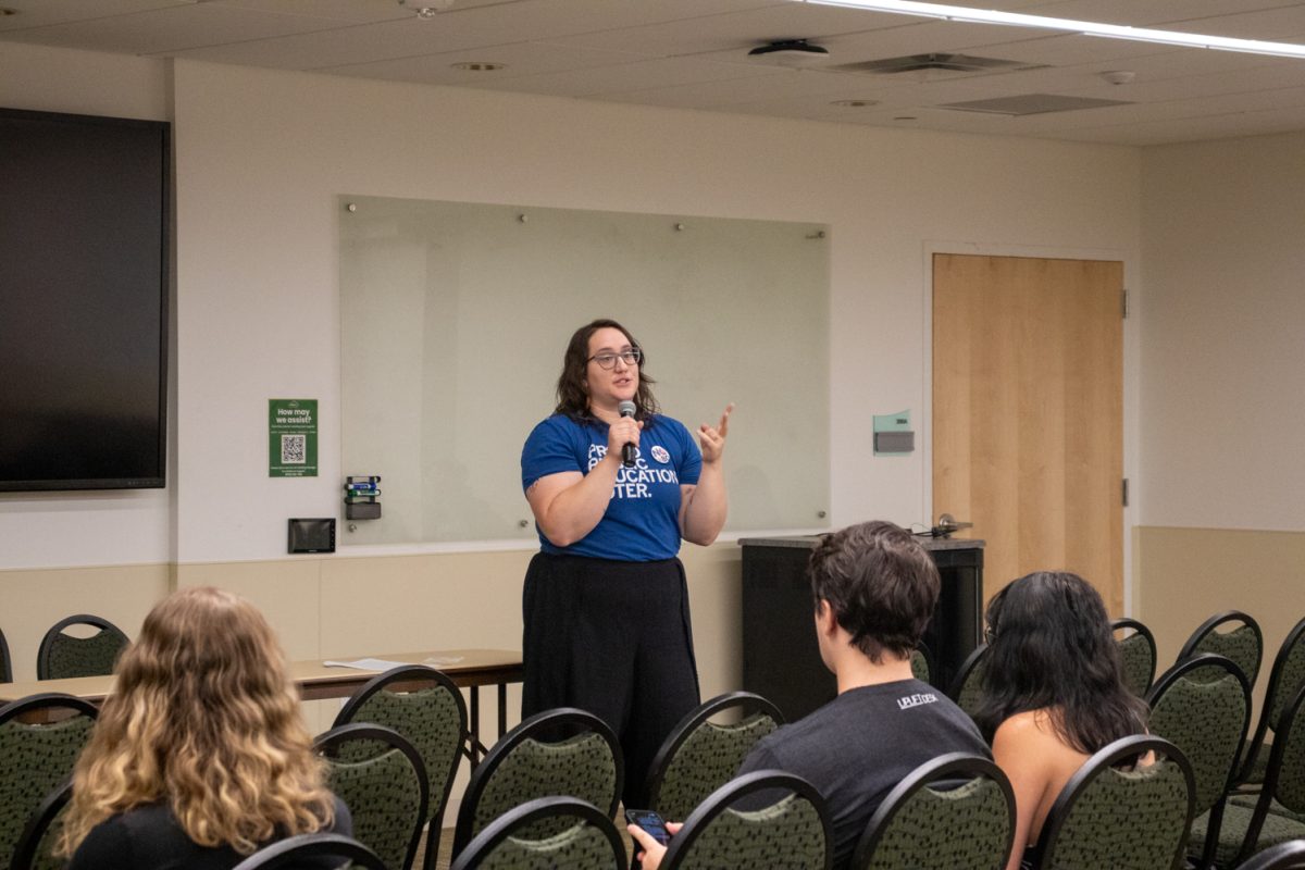 A person standing at the front of a room talking into a microphone.